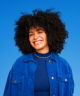 Fundo azul com mulher de cabelo black cacheado sorrindo